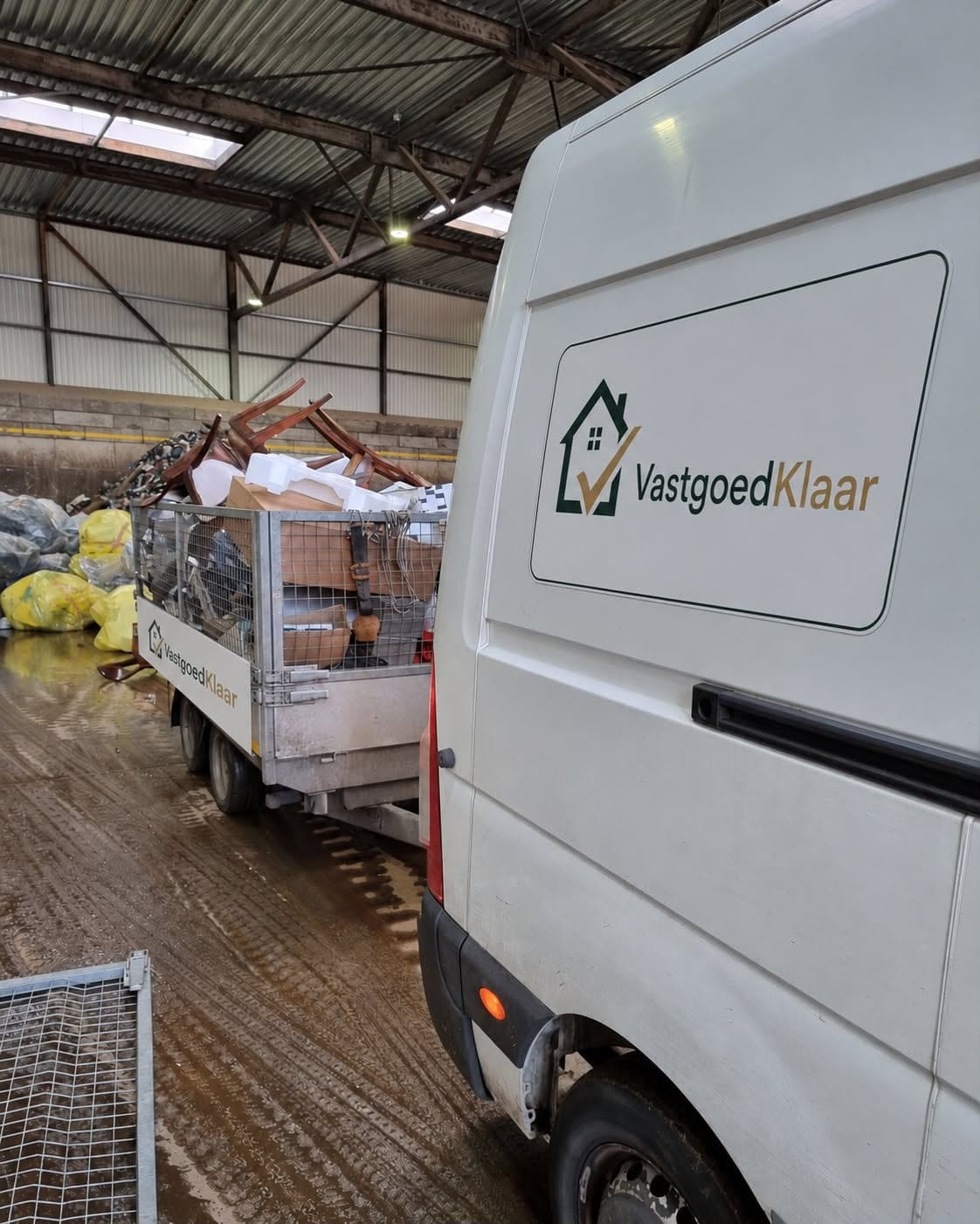 Bestelwagen en aanhanger van VastgoedKlaar met gesorteerd grofvuil voor correcte afvoer en recyclage